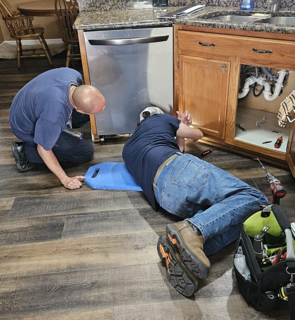 Plumbers working under sink